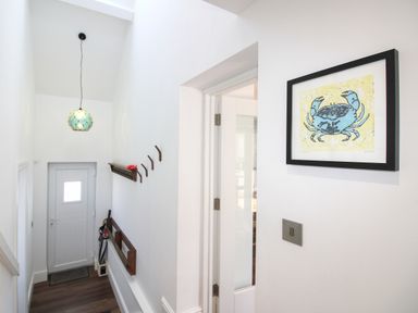 A hallway with a door and wall art at Lorrell in Salcombe