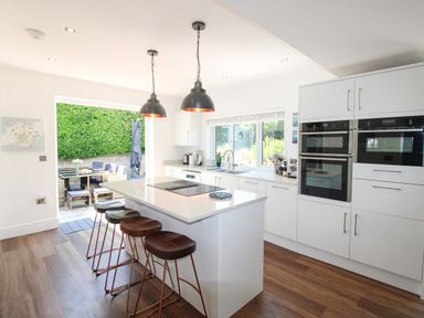 A kitchen with an island and bar stools at Lorrell in Salcombe