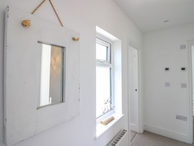 A hallway with a mirror and window at Lorrell in Salcombe