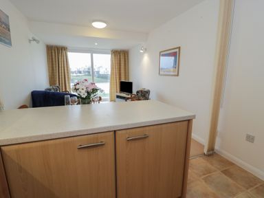 A living room with a kitchen counter and a tv at 10 Oakley Wharf in Porthmadog
