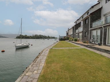 An outdoor view of a lawn and water with boats at Harbourside in Porthmadog