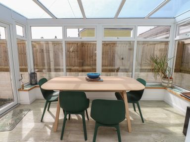 A conservatory with a table and chairs at Kiloran in Rhosneigr