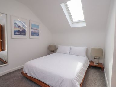 A bedroom with a bed and wall art at Kiloran Rhosneigr