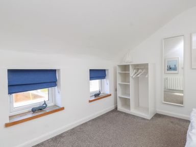 A bedroom with windows and a shelf unit at Kiloran in Rhosneigr