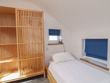 A bedroom with a bed and a wooden shelf at Kiloran in Rhosneigr