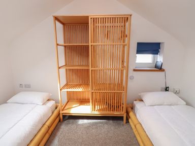 A bedroom with two beds and a wooden shelf at Kiloran in Rhosneigr