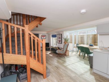 A living room with stairs and kitchen units at Kiloran in Rhosneigr