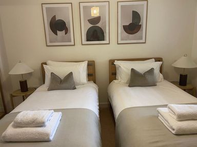 A bedroom with two single beds and artwork on the wall at Anchors Rest in St. Ives