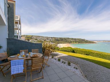 An outdoor area with a table and chairs overlooking a beach at Anchors Rest in St. Ives