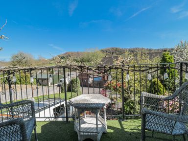 A balcony with chairs and a table overlooking a garden at 7 The Cedars Wotton-Under-Edge
