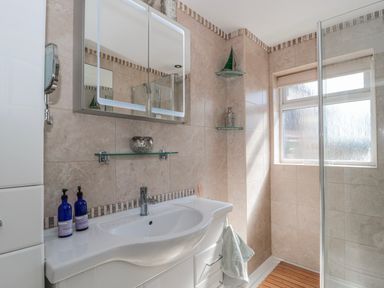 A bathroom featuring a sink, mirror, shower, and window at 7 The Cedars in Wotton-Under-Edge