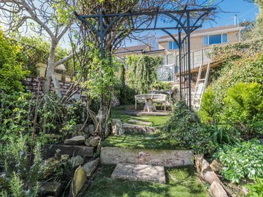 A garden with an archway and seating area at 7 The Cedars in Wotton-Under-Edge