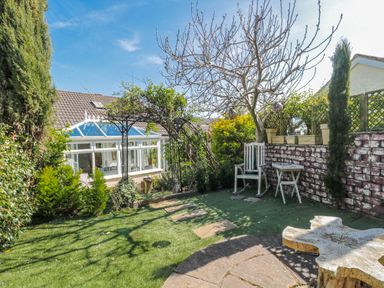 A garden with seating area and stone pathway at 7 The Cedars Wotton-Under-Edge