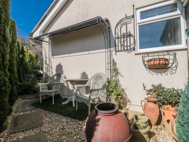 A garden with chairs and a table near terracotta pots at 7 The Cedars Wotton-Under-Edge