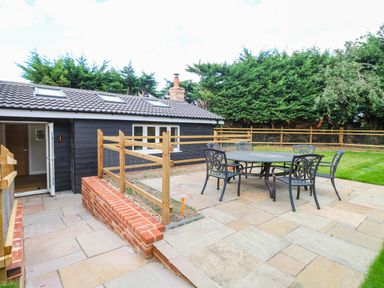 A garden with table and chairs near a house at Bramley Cottage in Worlingham