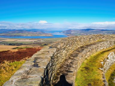 A view from a stone wall overlooking hills and a river at An Grianan Getaway in Burt