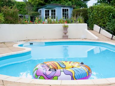 A swimming pool with a colorful float and a garden shed at Apartment 6 in Torquay