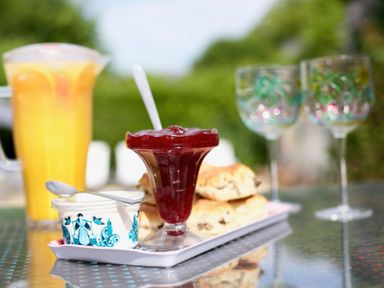 A table with juice, jam, cream, scones, and glasses at Apartment 6 in Torquay