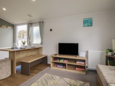 A living room with a table and television at Shamrocks Cove Caravan