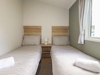 A bedroom with two beds and a bedside table at Shamrocks Cove Caravan