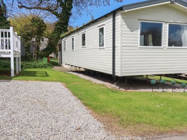 A caravan with gravel pathway and grassy area at Shamrocks Cove Caravan 