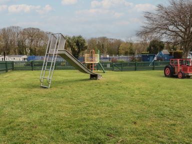 A slide and playground equipment in a grassy area at Shamrocks Cove Caravan