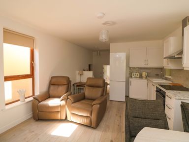 A living room with recliner chairs and a kitchen area at The Mews @ Suskar Laragh, County Wicklow
