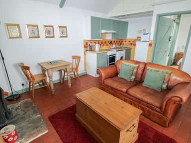 A living room with a sofa and dining area at Warbler Cottage in Cowbridge