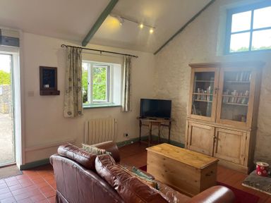 A living room with a sofa and a television at Warbler Cottage near Cowbridge