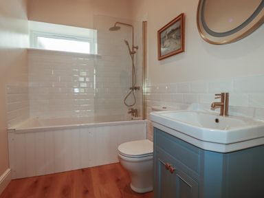 A bathroom with a bathtub, shower, sink, and toilet at Farthings, The Old Chapel in St. Austell