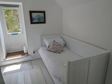 A bedroom with a bed and a door leading outside at Fairsands in Portreath
