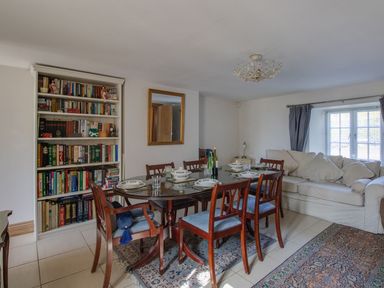 A dining room with a table and bookshelf at Honeypot Cottage in Weymouth
