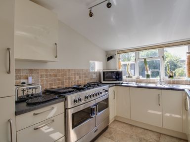 A kitchen with an oven, toaster and microwave at Honeypot Cottage in Weymouth