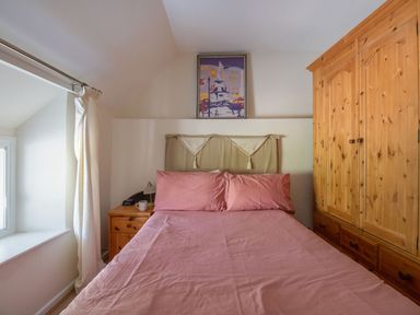 A bedroom with a bed and wardrobe at Honeypot Cottage Weymouth
