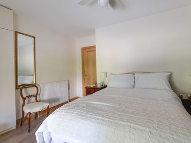 A bedroom with a bed and mirror at Honeypot Cottage in Weymouth
