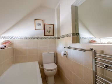 A bathroom with a bathtub and toilet at Honeypot Cottage in Weymouth