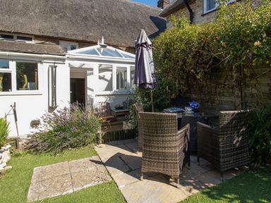 A garden with a table and chairs at Honeypot Cottage in Weymouth