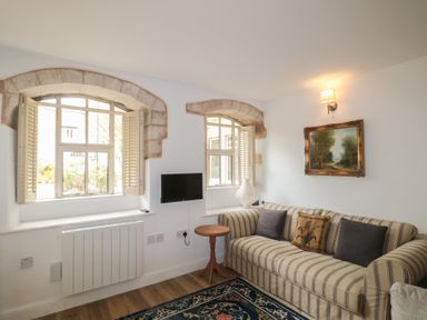 A living room with a sofa, table, and windows at Longfords Mill near Nailsworth