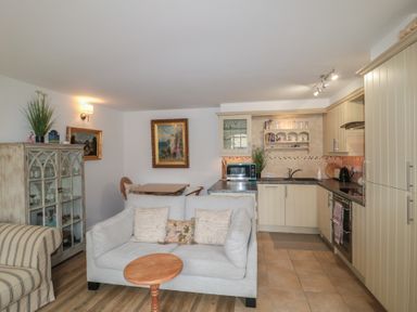 A living room with a sofa and kitchen appliances at Longfords Mill near Nailsworth