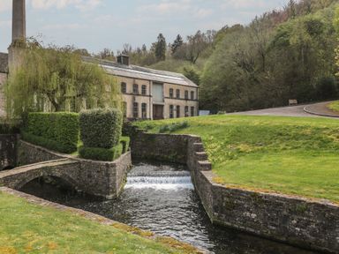 A building beside a stream and bridge at Longfords Mill near Nailsworth