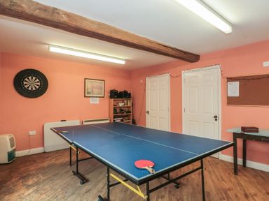 A recreational room with a ping pong table and dartboard at Longfords Mill, Minchinhampton