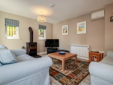 A living room with a television and coffee table at Stowaway Cottage in Padstow