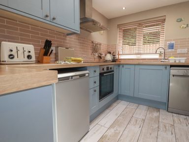 A kitchen with cabinetry, oven, and sink at Stowaway Cottage in Padstow
