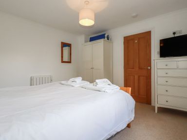 A bedroom with a bed and wardrobe at Stowaway Cottage in Padstow