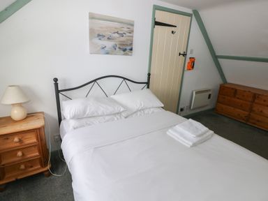 A bedroom with a bed and nightstand at Swallow Cottage in Cowbridge