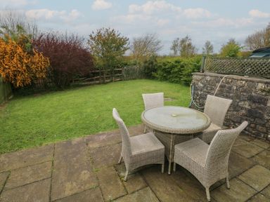 A garden with a table and chairs at Swallow Cottage in Cowbridge