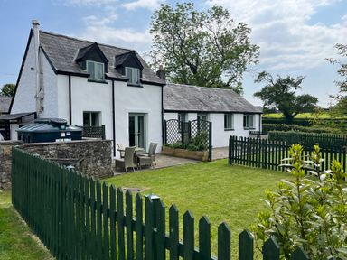 An outdoor area with a house, garden furniture and a fence at Swallow Cottage near Cowbridge