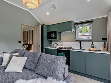 A kitchen with cabinets and a sofa at Prion 1.0 Pet in Llandyrnog
