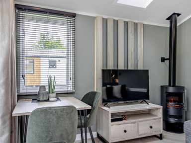 A living room with a table and a television at Prion 1.0 Pet in Llandyrnog