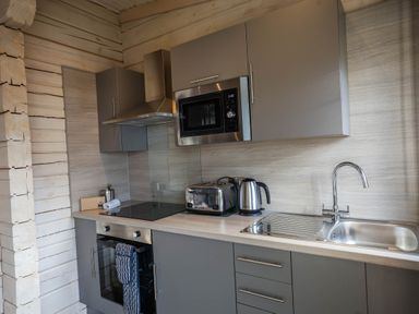 A kitchen with a stove, microwave, and sink at Pine Lodge Spa Carlton Miniott near Thirsk